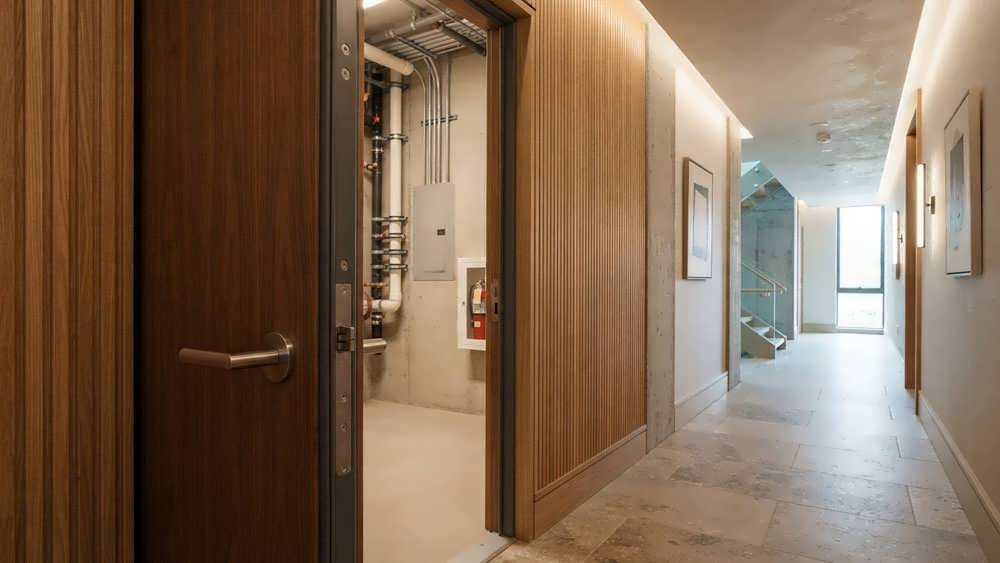درب ضد حریق مهندسی شده در راهروی یک ساختمان لوکس که به عنوان مانع منطقه بندی برای جلوگیری از گسترش آتش و دود عمل می کند