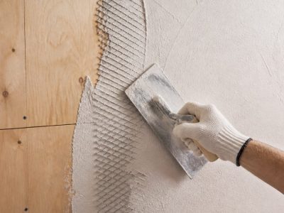 دیوار چوبی با توری رابیتس فلزی نصب‌شده و ابزار گچ‌کاری در کارگاه روشن